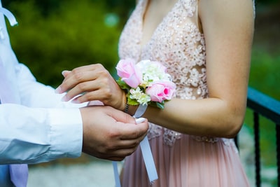 男人把粉色和白色的花饰放在女人的手上